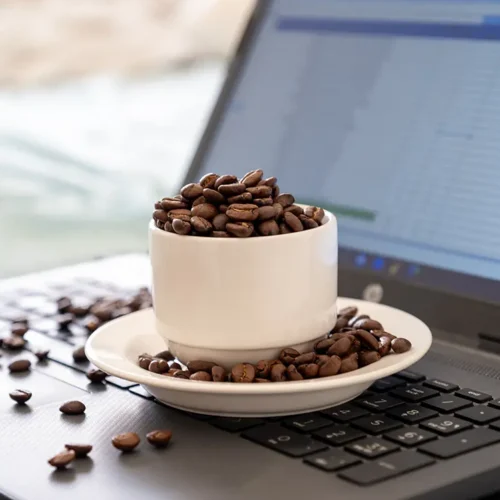 pc-cc-com-cup-coffee-that-full-coffee-beans-laptop-background-with-rim-light-represents-working-while-drinking-coffee